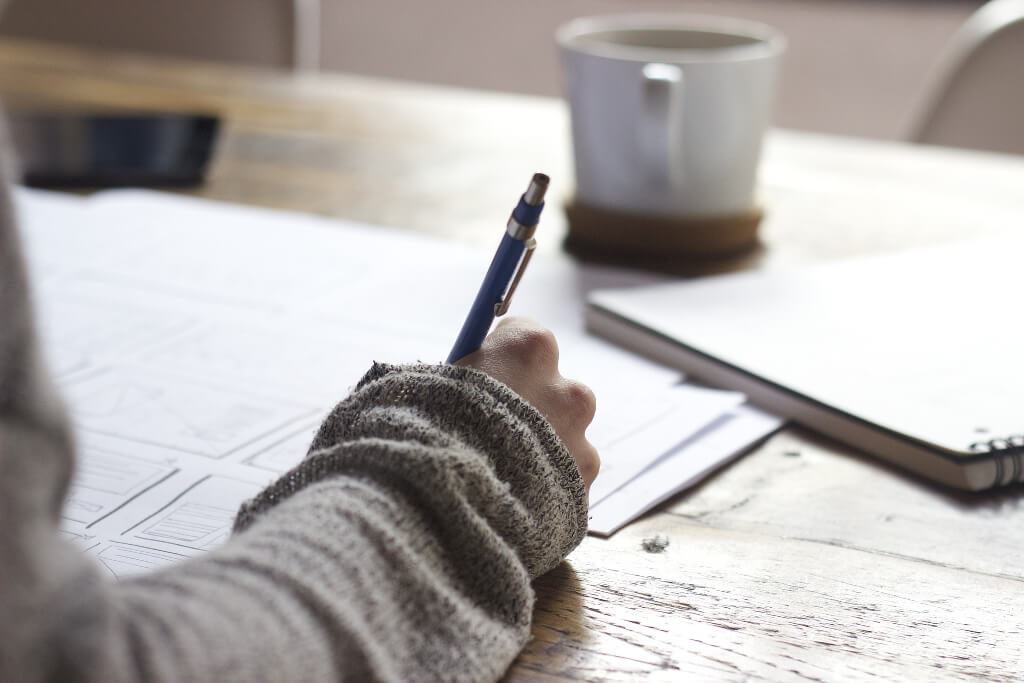Person writing with a pencil and paper
