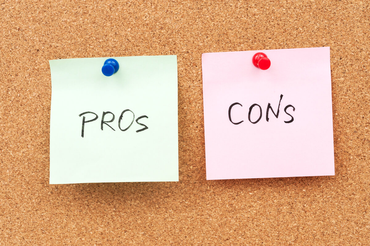 Green and pink post it notes that read "pros" and "cons" on a corkboard